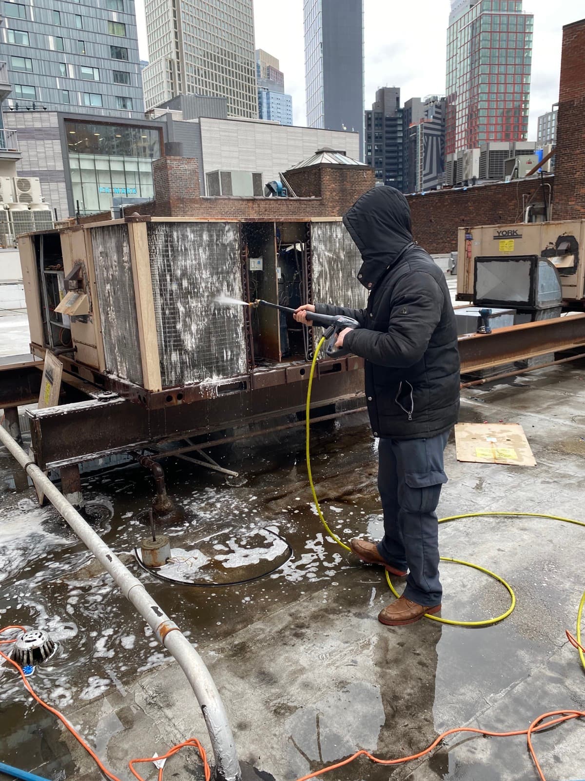 NHS technician cleaning a rooftop HVAC coil in New York City