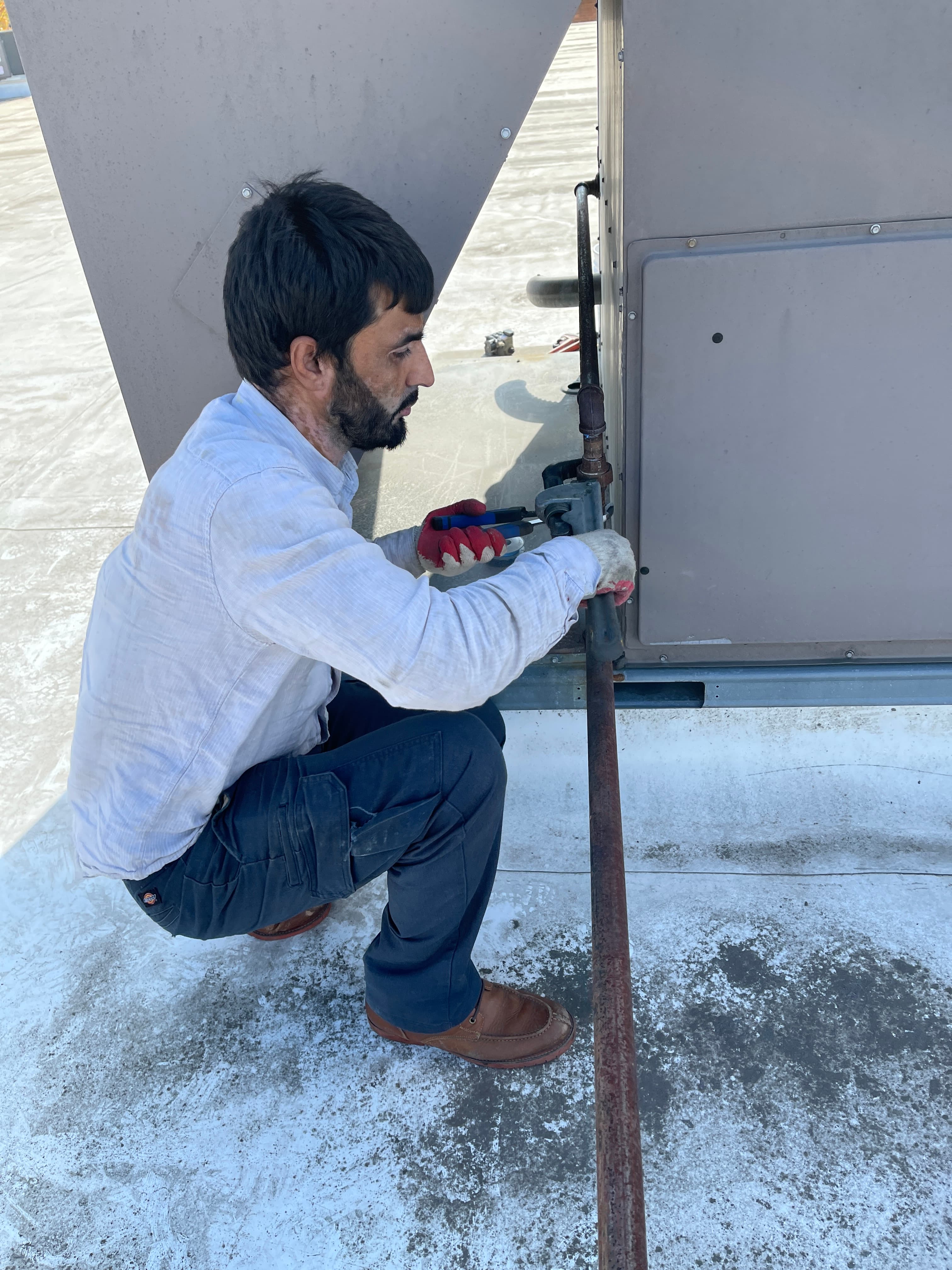 NHS technician repairing a rooftop HVAC unit